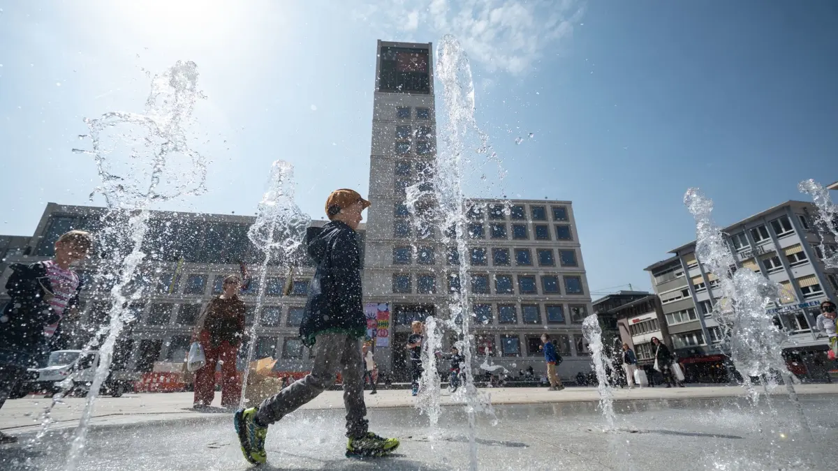 14.04.2022, Baden-Württemberg, Stuttgart: Ein Junge geht vor dem Rathaus durch ein Wasserfontänenfeld, das kurz zuvor in betrieb genommen wurde. Das Fontänenfeld mit 36 Wasserdüsen sprudelt von April bis Oktober auf dem neu gestalteten Marktplatz. Foto: Marijan Murat/dpa +++ dpa-Bildfunk +++