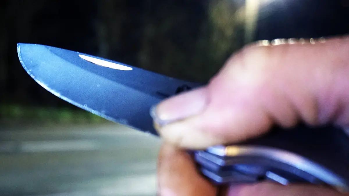 Kriminalität, Raub und Überfall / Raubüberfall - Symbolbilder Angriff mit Messer / Messerangriff - Symbolbilder .Messer als Kampfmittel und Waffe Eine Person hält bei Dunkelheit an einer Straße ein Messer in der Hand. *** Knife as a combat device and weapon A person holds a knife in his hand in the dark on a street
