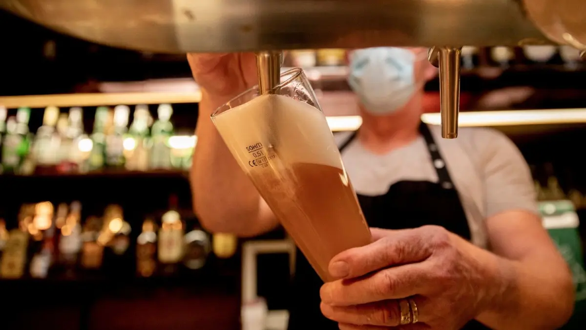 Nach monatelangem Corona-Lockdown in Deutschland fordert die Gastronomie jetzt eine konkrete Öffnungsperspektive.
05.10.2020, Berlin: Ein Wirt mit Maske zapft in einer Kneipe im Berliner Bezirk Wilmersdorf Bier in ein Glas. Berlin steuert bei der Zahl der Corona-Infektionen auf die nächste Warnstufe zu. Die steigenden Infektionszahlen in Deutschland bereiten zum Start der Feriensaison zunehmend Sorgen - vor allem die Situation in Berlin wird von den Ländern unterschiedlich bewertet. Foto: Christoph Soeder/dpa +++ dpa-Bildfunk +++