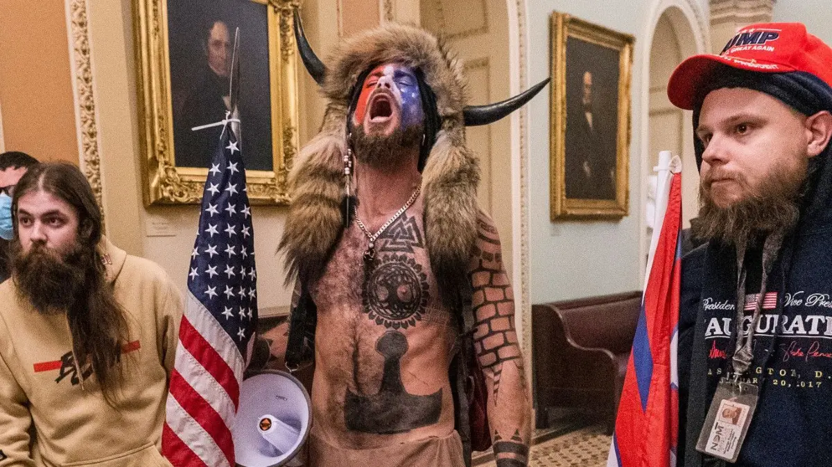 Eindringlinge auf dem Gang vor der Senatskammer im Kapitol in Washington.
06.01.2021, USA, Washington: Unterstützer von US-Präsident Trump stehen auf dem Gang vor der Senatskammer im Kapitol. Unter den Eindringlingen in das US-Kapitol am Mittwoch in Washington sind auch Anhänger der rechten «QAnon»-Verschwörungstheorie gewesen. Vor allem Aufnahmen eines Aktivisten mit nacktem Oberkörper und einer Fellmütze mit markanten Büffelhörnern kursieren im Netz. Der «Schamane» war mit anderen bis in den Sitzungssaal des Senats vorgedrungen. (zu dpa ««QAnon»-Anhänger bei Kongress-Sturm in vorderster Reihe vertreten») Foto: Manuel Balce Ceneta/AP/dpa +++ dpa-Bildfunk +++