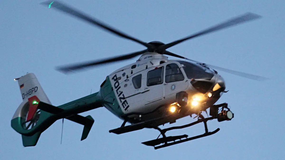 Polizeihubschrauber: ARCHIV - 24.02.2014, Bayern, München: Ein Polizeihubschrauber mit eingeschalteten Scheinwerfern. (zu dpa: «Polizeihubschrauber bei Vermisstensuche mit Laser geblendet») Foto: Rene Ruprecht/dpa +++ dpa-Bildfunk +++
