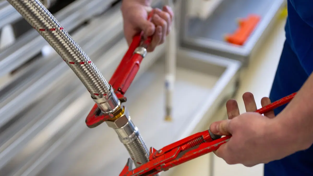 Handwerker mit Zangen: ARCHIV - 12.02.2024, Berlin: Ein Azubi verbindet zwei Schläuche mit Zangen im Kompetenzzentrum der Innung Sanitär, Heizung und Klima Berlin. (zu dpa: «Umfrage: Fachkräftemangel trifft Mittelstand mehr als teure Energie») Foto: Monika Skolimowska/dpa +++ dpa-Bildfunk +++