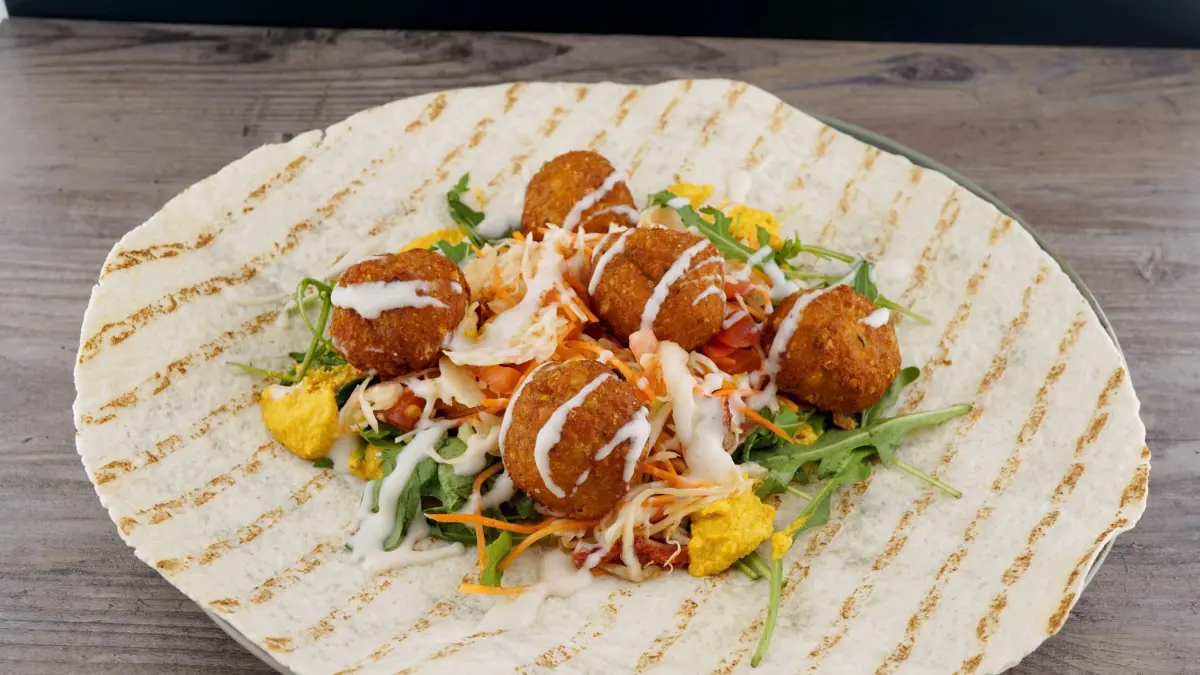 Der offene Wrap hat eine Füllung aus Falafel und Salat
