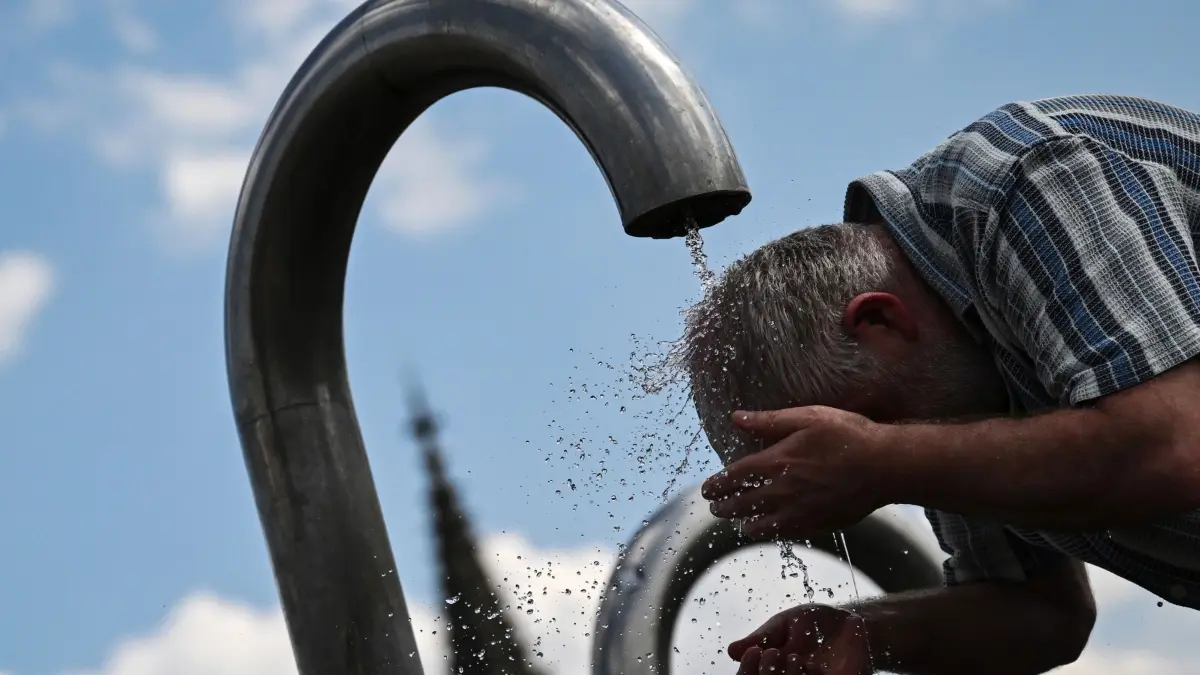 Sommer in Stuttgart: 19.07.2024, Baden-Württemberg, Stuttgart: Ein Passant kühlt sich an einem Mineralwasserbrunnen ab. Foto: Marijan Murat/dpa +++ dpa-Bildfunk +++