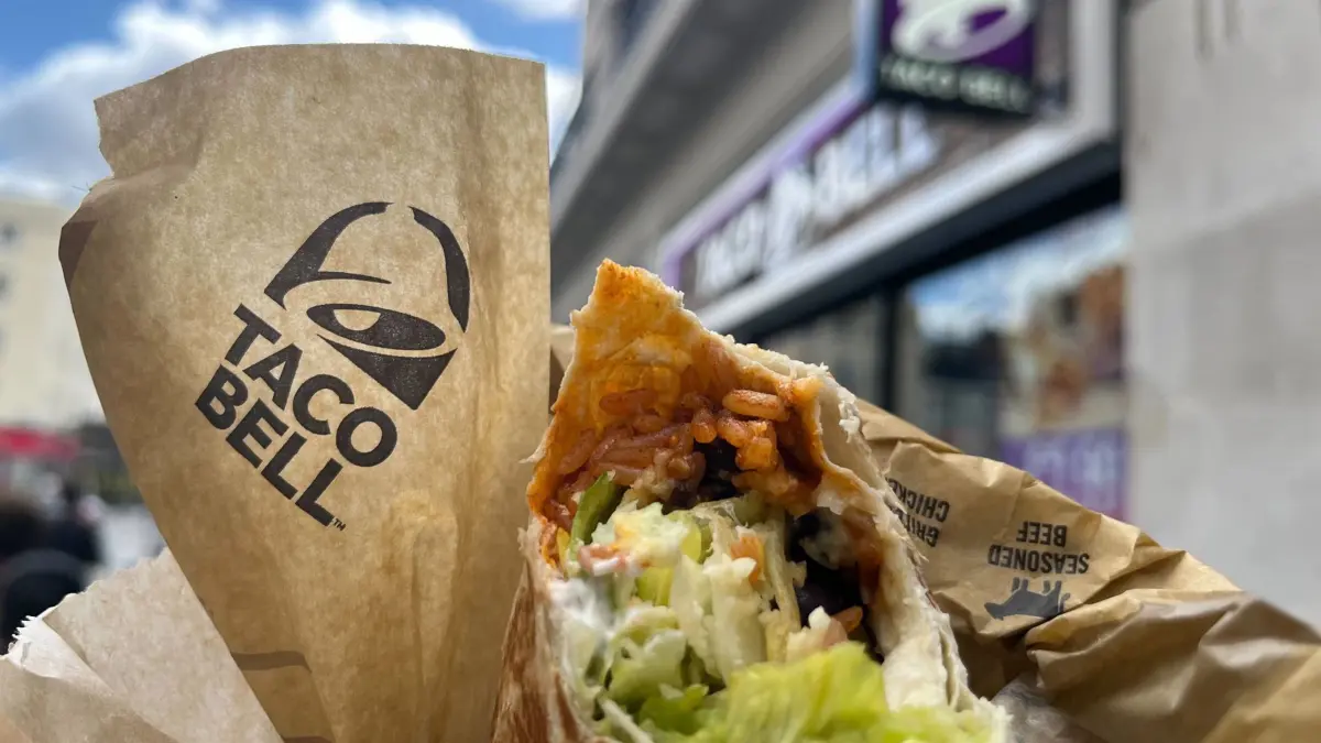 ARCHIV - 15.05.2024, Großbritannien, London: Das Taco Bell-Logo und ein Burrito sind vor einer Filiale der Kette in London zu sehen. (zu dpa: «Taco Bell setzt auf KI für Annahme von Bestellungen») Foto: Julia Kilian/dpa +++ dpa-Bildfunk +++