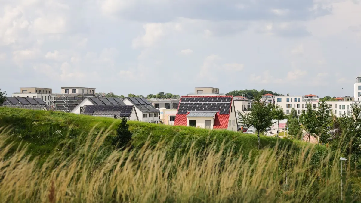 Einfamilienhäuser in einem Neubaugebiet: ARCHIV - 27.06.2024, Bayern, Herzogenaurach: Mehrfamilienhäuser (r) und Einfamilienhäuser, einige Häuser mit Photovoltaik auf dem Dach, sind in einem Neubaugebiet zu sehen. (zu dpa: «Studie: Privathaushalte investieren in Energiewende») Foto: Christian Charisius/dpa +++ dpa-Bildfunk +++