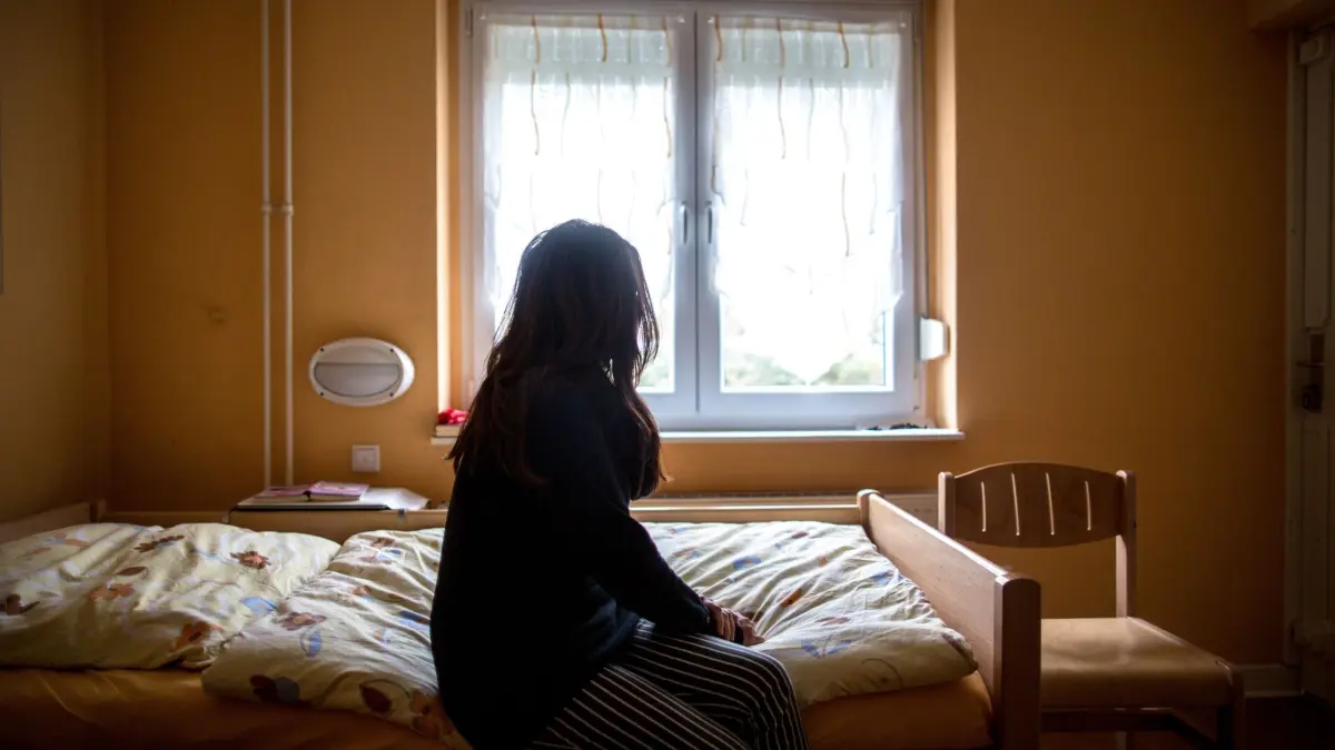 Frau, die im Frauenhaus untergebracht war, wurde abgeschoben.: ARCHIV - 12.11.2015, Nordrhein-Westfalen, Herne: Eine Frau sitzt in einem Frauenhaus auf einem Bett. Eine 28-jährige Türkin, die mit ihren beiden Kindern in einem Hamburger Frauenhaus untergebracht war, ist abgeschoben worden. (zu dpa: «28-Jährige und ihre beiden Kinder aus Frauenhaus abgeschoben») Foto: Maja Hitij/dpa +++ dpa-Bildfunk +++