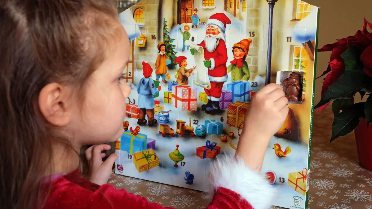 Stichwort: Advent: Virginia oeffent das erste Fenster des Adventskalenders (Themenfoto). Advent - vom lateinischen Wort "adventus" fuer Ankunft - ist die Zeit der Vorbereitung auf Weihnachten. In die Zeit des Advents faellt am 21. Dezember auch die Wintersonnenwende. Die Tage werden danach wieder laenger und lassen das Ende von Winter und Dunkelheit erahnen. Die vier Adventssonntage sollen in der christlichen Tradition auf die wachsende Naehe Gottes zu den Menschen einstimmen, fuer die die Geburt Jesu an Weihnachten steht. (Siehe epd-Stichwort vom 21.11.2024) *** Local Caption *** 00324481