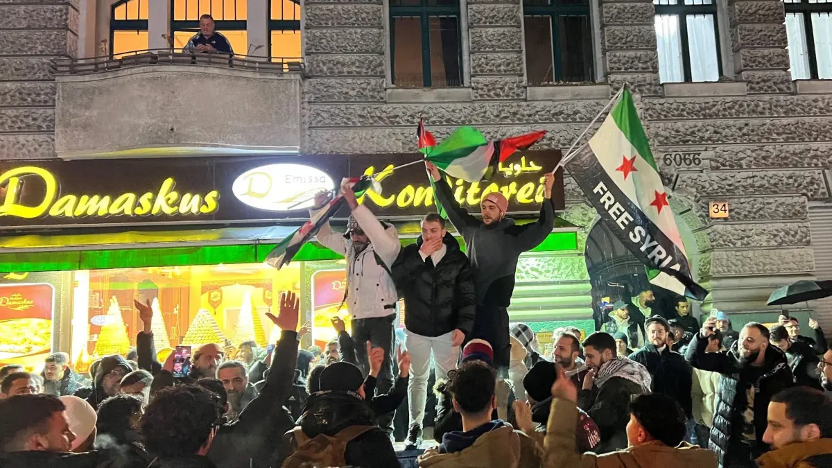 Syrer in Berlin: 07.12.2024, Berlin: Syrer versammeln sich im Bezirk Neukölln mit Flaggen vor der Bäckerei Damaskus und feiern den Vormarsch der Rebellen auf Damaskus. Aufständische übernehmen in Syrien mit hoher Geschwindigkeit die Kontrolle über Städte und ganze Landstriche. Foto: Julius-Christian Schreiner/dpa +++ dpa-Bildfunk +++