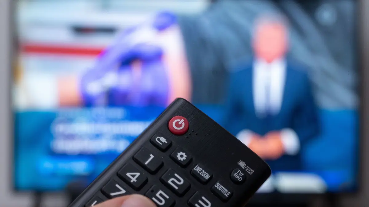 ARCHIV - Ein Mann hält eine Fernbedienung vor einen Fernseher, auf dem die "Tagesschau" läuft. Für die Ermittlung der Höhe des künftigen Rundfunkbeitrags ist ein erster wichtiger Schritt erfolgt. Die öffentlich-rechtlichen Sender von ARD, ZDF und Deutschlandradio haben ihren Finanzbedarf bei der unabhängigen Finanzkommission KEF angemeldet, wie die Medienhäuser am 28.04.2023 mitteilten. Konkrete Höhen wurden nicht genannt. (zu dpa "Rundfunkbeitrag: Öffentlich-rechtliche Sender melden Finanzbedarf an") +++ dpa-Bildfunk +++