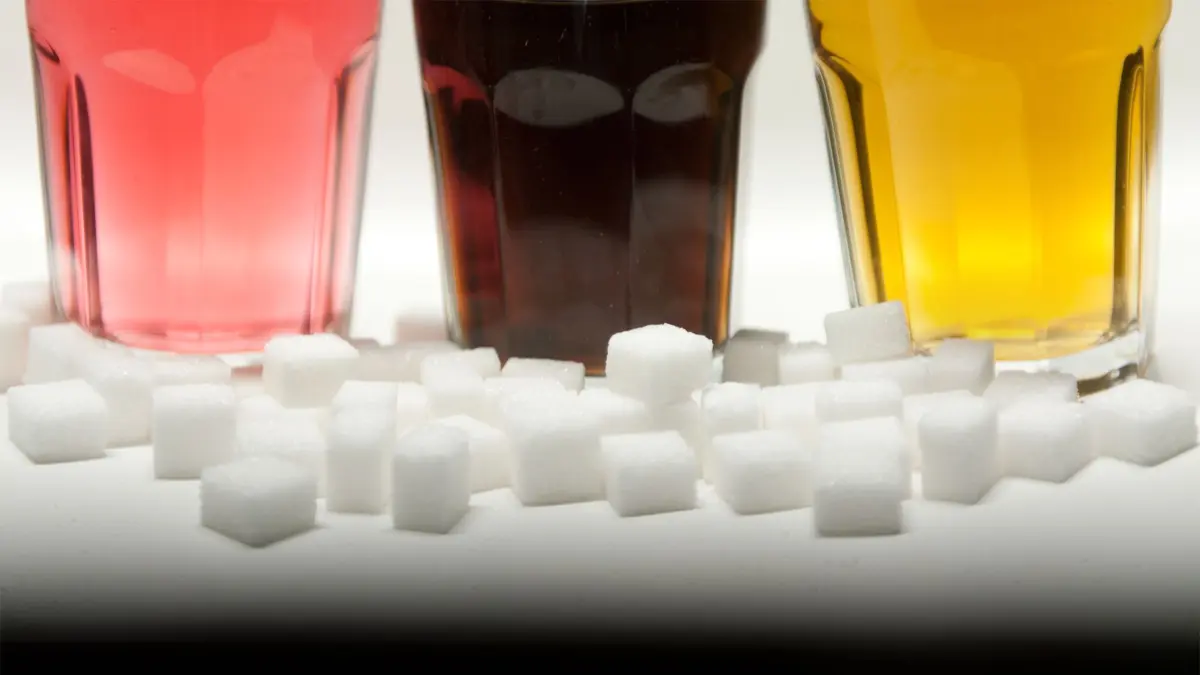 ARCHIV - 23.08.2016, Berlin: Drei Gläser gefüllt mit roter Limonade, Cola und einem Energy-Drink stehen neben Zuckerwürfeln auf einem Tisch. Bei vielen Fertigprodukten aus dem Supermarkt kommt eine angestrebte Verringerung von Zucker, Fett und Salz nach einer Auswertung für die Bundesregierung zu wenig voran. (zu dpa: «Softdrinks erhöhen Risiko für Diabetes und Herz-Kreislauf-Krankheiten») Foto: Monika Skolimowska/dpa +++ dpa-Bildfunk +++