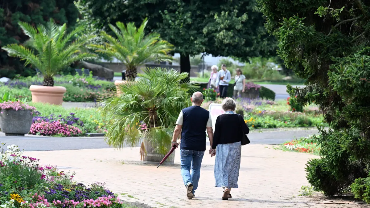 Ein Paar spaziert mit einem Regenschirm bewaffnet durch den Rheinpark. Meteorologen sagen für die nächste Woche einen Mix aus Regen, Sonne und Bewölkung voraus. +++ dpa-Bildfunk +++