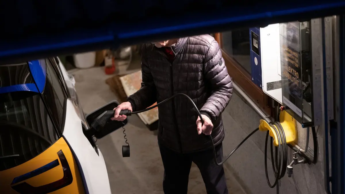 Ein Mann lädt sein E-Auto an einer Wallbox: ARCHIV - Die Kosten für E-Autos können im Vergleich zu Verbrennern deutlich niedriger sein, insbesondere bei Aufladung zu Hause an der Wallbox (zu dpa: «Sind E-Autos bei Verbrauchskosten günstiger als Verbrenner?») Foto: Marijan Murat/dpa/dpa-mag - Honorarfrei nur für Bezieher des Dienstes dpa-Magazin +++ dpa-Magazin +++