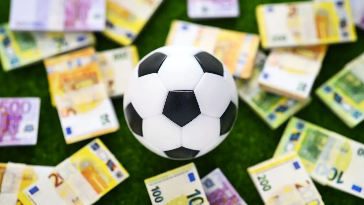 Symbolfoto für Polizeikosten bei Fanausschreitungen: Fußball mit Geldscheinbündel, Symbolfoto für Polizeikosten bei Fanausschreitungen