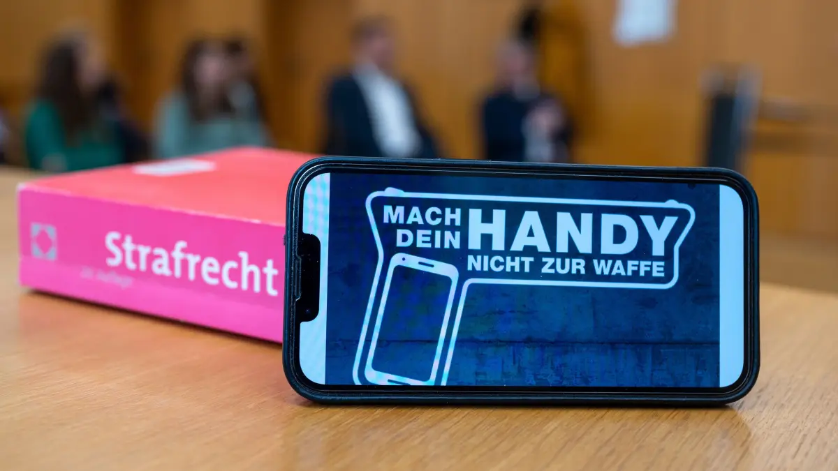 „Mach dein Handy nicht zur Waffe“ steht auf dem Display eines Smartphones. Seit 2021 ist Kampagne Teil eines Gemeinschaftsprojekts der bayerischen Justiz- und Kultusministerien. (zu dpa «"Schick' Nacktbilder" - Wenn Schüler sich strafbar machen») +++ dpa-Bildfunk +++