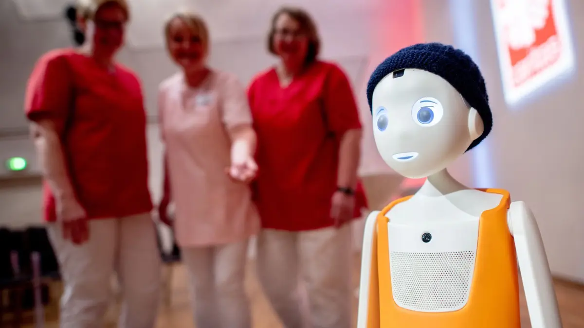 36. Tag der Altenpflege - KI und Technik in der Pflege: 20.03.2025, Niedersachsen, Cloppenburg: Pflegefrachkräfte sprechen beim Tag der Altenpflege in der Stadthalle mit dem Pflegeroboter „Navel“. Der 36. Tag der Altenpflege in Cloppenburg findet in diesem Jahr zum Thema Künstliche Intelligenz und Technik in der Pflege statt. Veranstalter sind der Landes-Caritasverband für Oldenburg (LCV) sowie die Arbeitsgemeinschaft Altenhilfe. Foto: Hauke-Christian Dittrich/dpa +++ dpa-Bildfunk +++