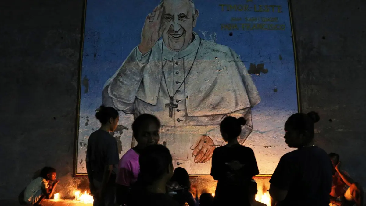 Papst Franziskus gestorben - Osttimor: 21.04.2025, Osttimor, Dili: Menschen zünden vor einem Wandbild des verstorbenen Papstes Franziskus Kerzen an. Foto: Uncredited/AP/dpa +++ dpa-Bildfunk +++