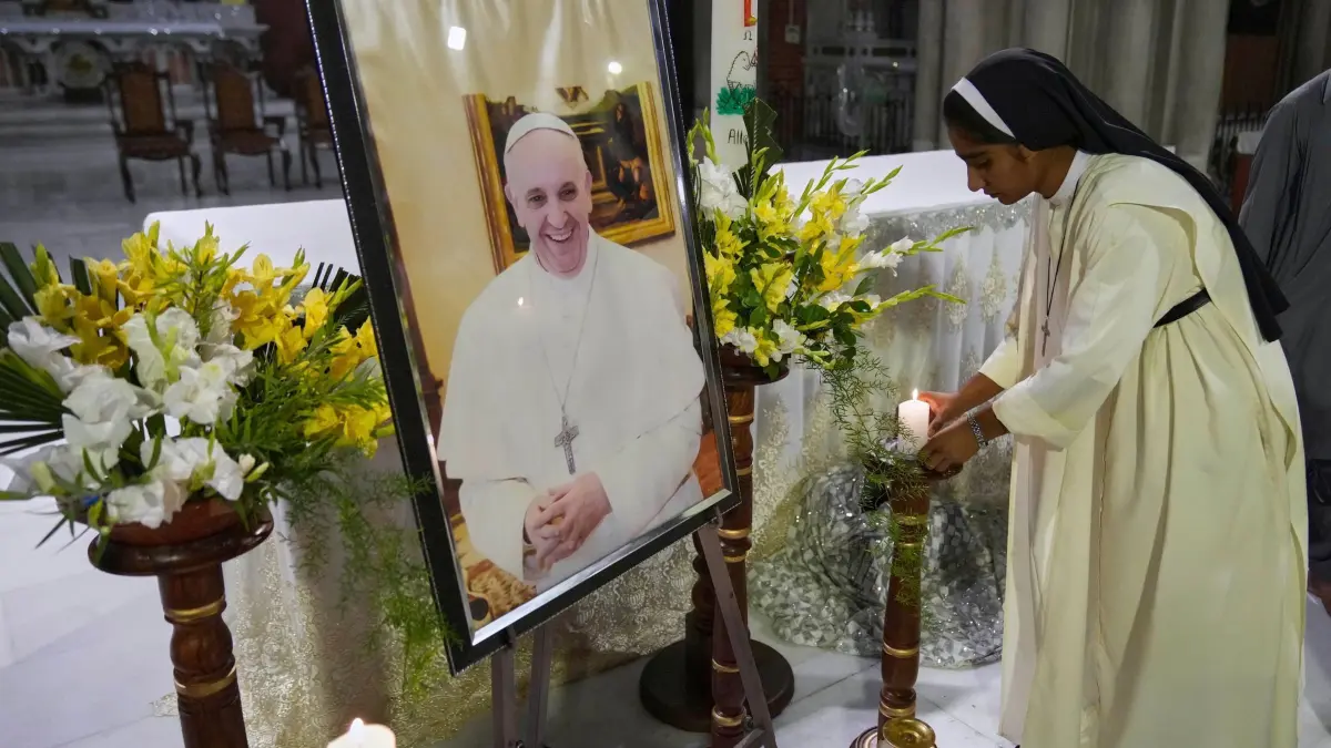 Papst Franziskus gestorben - Pakistan: 21.04.2025, Pakistan, Lahore: Eine Nonne stellt eine Kerze vor das Porträt von Papst Franziskus während einer Gebetszeremonie in der Kathedrale der Auferstehung nach der Bekanntgabe des Todes des Kirchenoberhaupts. Foto: K.M. Chaudary/AP/dpa +++ dpa-Bildfunk +++