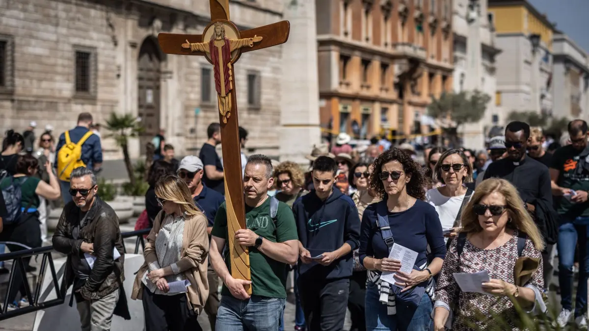 Papst Franziskus gestorben - Vatikan: 21.04.2025, Vatikan, Vatikanstadt: Ein Pilger, der ein Kreuz trägt, betritt den Petersplatz am Tag des Todes von Papst Franziskus. Der argentinische Pontifex, der die katholische Kirche seit 2013 leitete, starb am Montag und hinterließ einen tiefen Eindruck bei Millionen Menschen auf der ganzen Welt. Foto: Oliver Weiken/dpa +++ dpa-Bildfunk +++