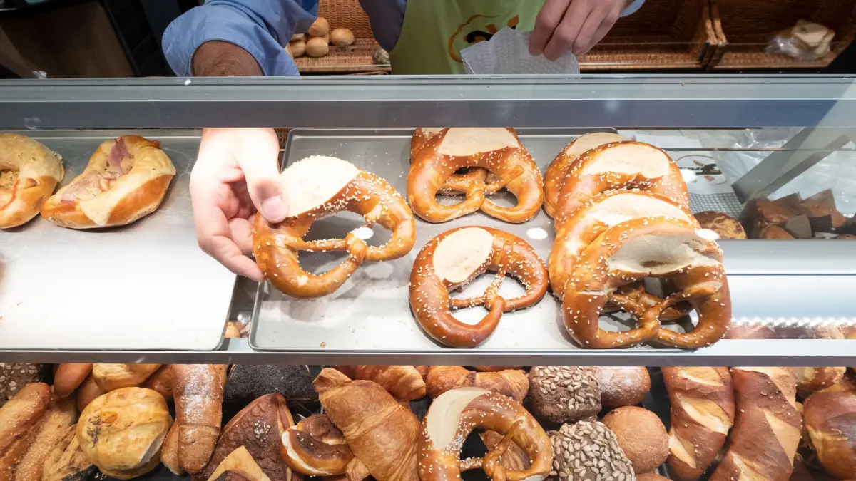 ARCHIV - 17.10.2019, Baden-Württemberg, Stuttgart: Ein Hand nimmt in einer Bäckerei eine Brezel aus einer Auslage. (zu dpa: «Handwerkstag: Kunden von Bäckern und Metzgern sparen») Foto: Bernd Weissbrod/dpa +++ dpa-Bildfunk +++