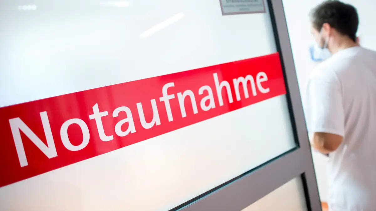 Ein Krankenpfleger steht in einem Krankenhaus neben einer Glastür mit der Aufschrift «Notaufnahme». (zu dpa: «Immer weniger Kliniken in Deutschland - Kommt große Reform?») +++ dpa-Bildfunk +++