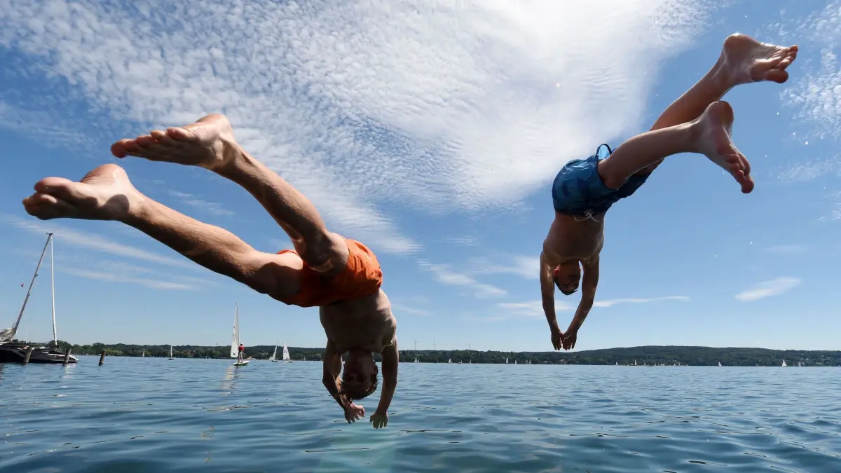 Zwei junge Männer springen am Starnberger See ins Wasser: ARCHIV - Flachköpper macht aua! Einen Kopfsprung ins Wasser sollte man nur wagen, wenn es erlaubt und das Wasser sicher tief genug ist. (zu dpa: «6 typische Gefahren beim Baden - und wie man sich schützt») Foto: Tobias Hase/dpa/dpa-tmn - Honorarfrei nur für Bezieher des dpa-Themendienstes +++ dpa-Themendienst +++