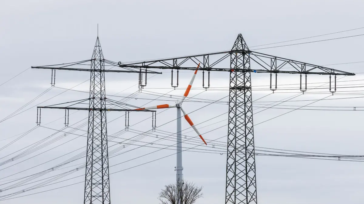 Stromleitungen vor Windrad: ARCHIV - 01.02.2022, Baden-Württemberg, Herbolzheim: Ein Windrad steht neben dem Mast einer Hochspannungsleitung und dreht sich im Wind. Die Bundesnetzagentur will neue Netzentgelt-Rabatte für die Industrie einführen. (zu dpa: «Netzkosten haben sich seit 2015 verdoppelt - Kritik vom BSW») Foto: Philipp von Ditfurth/dpa +++ dpa-Bildfunk +++