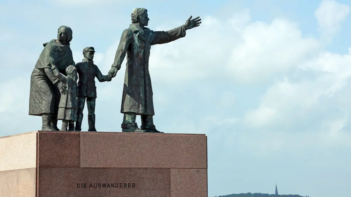 Deutsches Auswandererhaus vor 20 Jahren eroeffnet: Unweit des Deutschen Auswandererhauses, zwischen Weser und Neuem Hafen an der Seebaederkaje auf dem Willy-Brandt-Platz, steht eine Bronzeskulptur, die eine vierkoepfige Auswandererfamilie auf einem quaderfoermigen Sockel aus Granit zeigt (Foto vom 26.07.2025). Der amerikanische Bildhauer Frank Varga aus Detroit hat sie 1986 geschaffen. Der Vater schaut nach vorne, Richtung Neue Welt, die Mutter dreht sich noch einmal aus, ein letzter Blick in Richtung der alten Heimat. Im Neuen Hafen haben zwischen 1830 und 1974 mehr als sieben Millionen Menschen ein Schiff bestiegen, um auszuwandern. (Siehe epd-Feature vom 31.07.2025)