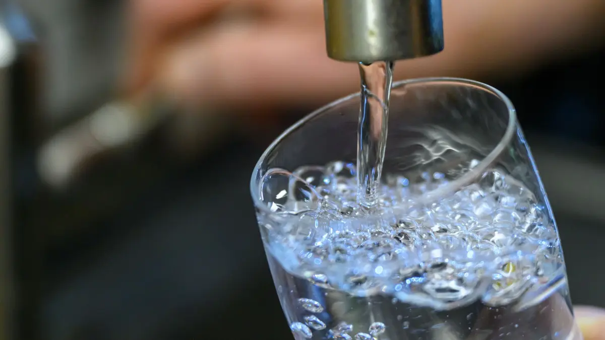 Keime im Trinkwasser: ARCHIV - 24.07.2025, Sachsen, Chemnitz: Trinkwasser läuft in einer Küche in Chemnitz in ein Glas. Die aktuell hochsommerlichen Temperaturen können für eine erhöhte Keimbelastung im Trinkwasser sorgen.. (Symbolfoto) (zu dpa: «Hitzewelle kann Trinkwasserqualität beeinträchtigen») Foto: Hendrik Schmidt/dpa +++ dpa-Bildfunk +++
