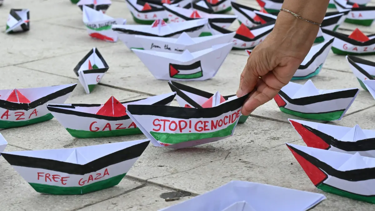 A flotilla of paper boats reading "Stop Genocide" "Free Gaza" are laid on the ground during a demonstration in support of Gaza and Palestinian people at Venice Lido during the 82nd Venice International Film Festival, on August 30, 2025. (Photo by Stefano RELLANDINI / AFP)