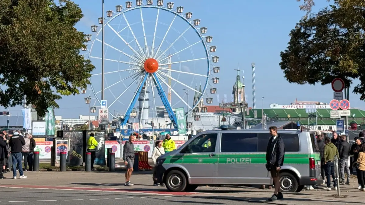Oktoberfest bleibt nach Bombendrohung vorerst geschlossen: 01.10.2025, Bayern, München: Ein Polizeiwagen steht am Gelände vom Oktoberfest (Bestmögliche Qualität) . Im Hintergrund ist das Riesenrad zu sehen. Das Münchner Oktoberfest bleibt wegen einer Sprengstoffdrohung bis mindestens 17.00 Uhr geschlossen. Wie die Stadt auf ihrer Homepage mitteilte, gibt es einen Zusammenhang mit einer Explosion im Münchner Norden und ein entsprechendes Schreiben des Täters. Foto: Christof Rührmaier/dpa - ACHTUNG: Verwendung nur im vollen Format +++ dpa-Bildfunk +++