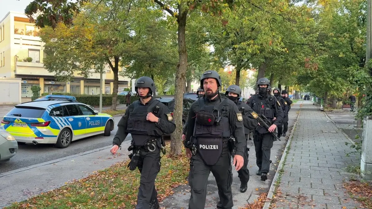 Brand in München - Großeinsatz von Polizei und Feuerwehr: 01.10.2025, Bayern, München: Polizisten mit Schutzwesten gehen über einen Fußweg. Ein Brand in einem Münchner Einfamilienhaus hat einen Großeinsatz von Polizei und Feuerwehr ausgelöst. Es kam deswegen zu größeren Verkehrsbehinderungen, eine Gefahr für die Bevölkerung bestehe nicht, sagte ein Polizeisprecher am Morgen Foto: Roland Freund/dpa +++ dpa-Bildfunk +++