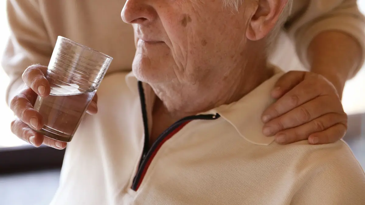 Eine Frau hilft einem Mann beim Trinken: ILLUSTRATION - Die Pflege eines Angehörigen kann sowohl körperlich, als auch emotional ziemlich anstrengend sein. Foto: Mascha Brichta/dpa-mag - Honorarfrei nur für Bezieher des Dienstes dpa-Magazin +++ dpa-Magazin +++