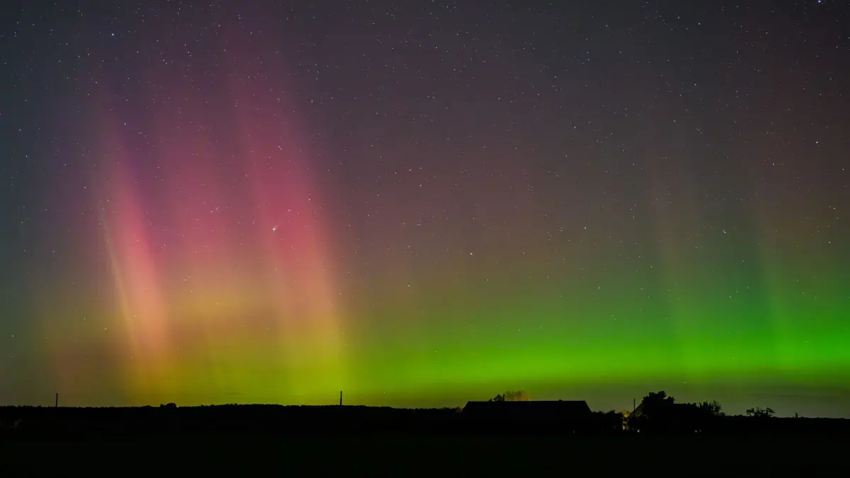 Polarlicht und Komet leuchten am Nachthimmel: 18.10.2025, Brandenburg, Lietzen: Polarlichter und der Komet Lemmon «C/2025 A6» (Bildmitte etwas links) leuchten am Nachthimmel über der Landschaft im östlichen Brandenburg. Nordlichter (Aurora borealis) werden durch eine Wolke elektrisch geladener Teilchen eines Sonnensturms in der Erdatmosphäre erzeugt. Der farbliche Effekt wird hierbei durch die Digitalkamera bei einer Langzeitbelichtung von etwa zehn Sekunden noch verstärkt. Foto: Patrick Pleul/dpa +++ dpa-Bildfunk +++