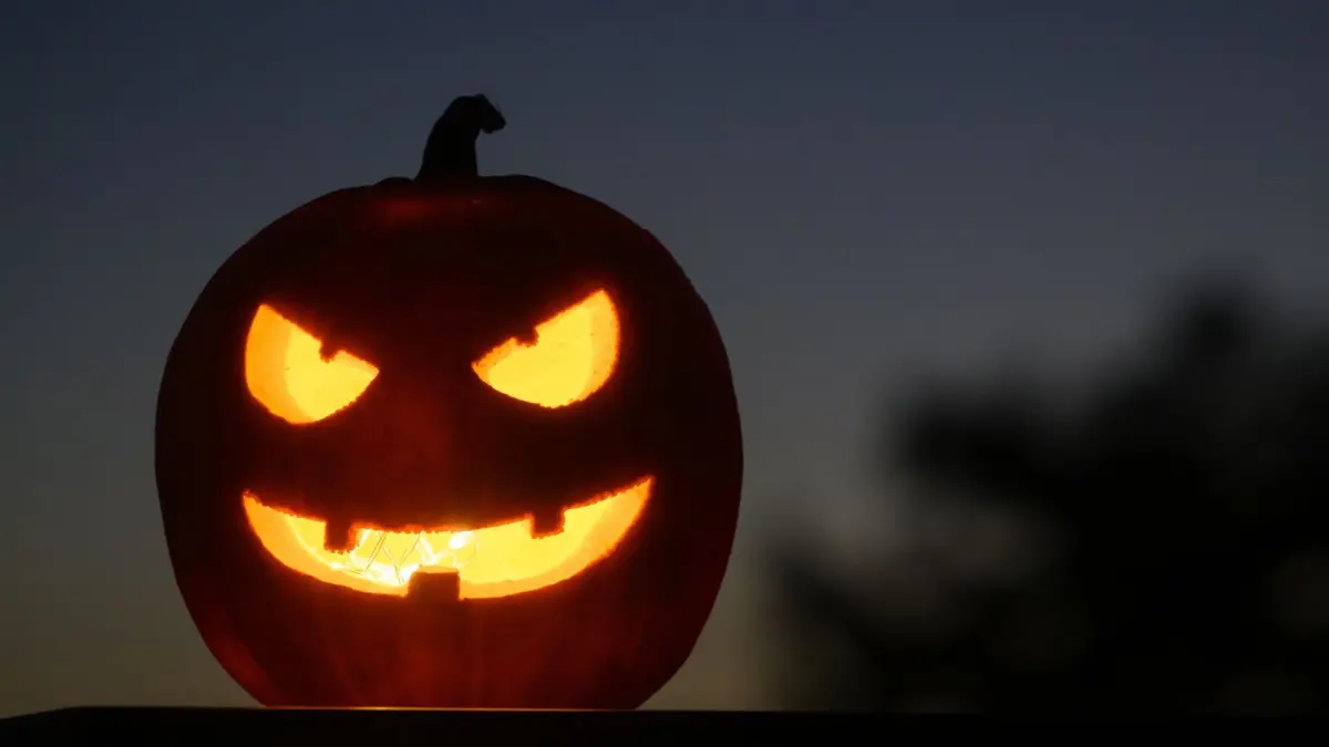 ARCHIV - 28.10.2024, Schweiz, Daillens: Als Halloween-Dekoration steht ein ausgehöhlter, beleuchteter Kürbis mit einem geschnitzten grinsenden Gesicht in einem Garten in Daillens, Schweiz. Halloween ist ein Fest, das am 31. Oktober gefeiert wird, bei dem sich die Menschen verkleiden, Kürbisse schnitzen, Partys feiern und Kinder um Süßes oder Saures bitten. (zu dpa: «Grusel-Tipps rund um Halloween in Rheinland-Pfalz») Foto: Laurent Gillieron/KEYSTONE/dpa +++ dpa-Bildfunk +++