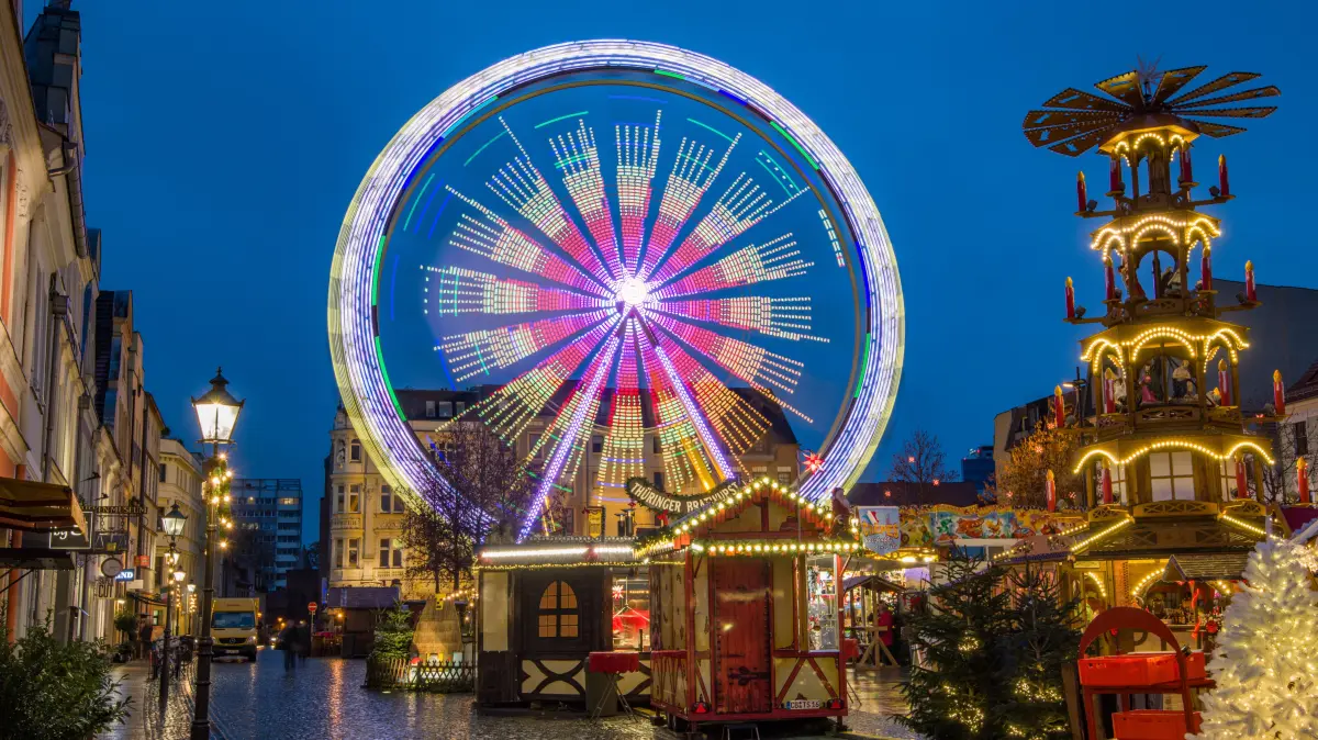 11.12.2018, Brandenburg, Cottbus: Die Lichter vom Riesenrad und Pyramide auf dem Weihnachtsmarkt spiegeln sich auf den vom Regen nassen Pflastersteinen des Altmarktes. Foto: Patrick Pleul/dpa-Zentralbild/ZB +++ dpa-Bildfunk +++