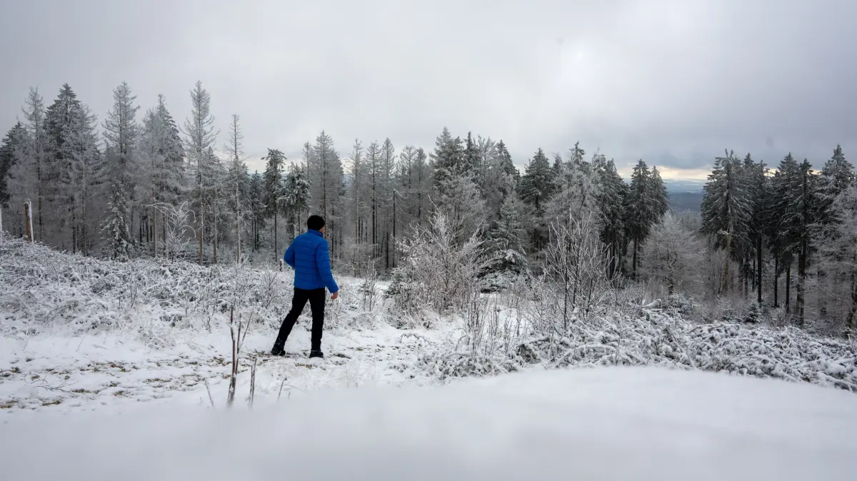 Ein Mann geht am verschneiten Gipfel des Erbeskopf durch die verschneite Landschaft. Der Skilift ist noch nicht in Betrieb, Wintersport zur Zeit noch nicht möglich. +++ dpa-Bildfunk +++
