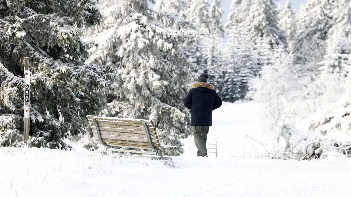 Ein Mann geht durch die verschneite Landschaft am Kahlen Aasten. Die Vorboten des Winters sind in Nordrhein-Westfalen angekommen. +++ dpa-Bildfunk +++