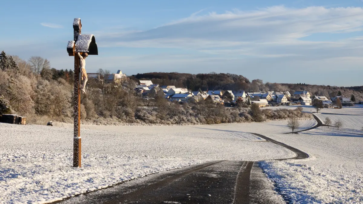Schnee liegt am Morgen auf der Schwäbischen Alb bei Dürrenwaldstetten auf einem Weg und einem Wegkreuz. +++ dpa-Bildfunk +++