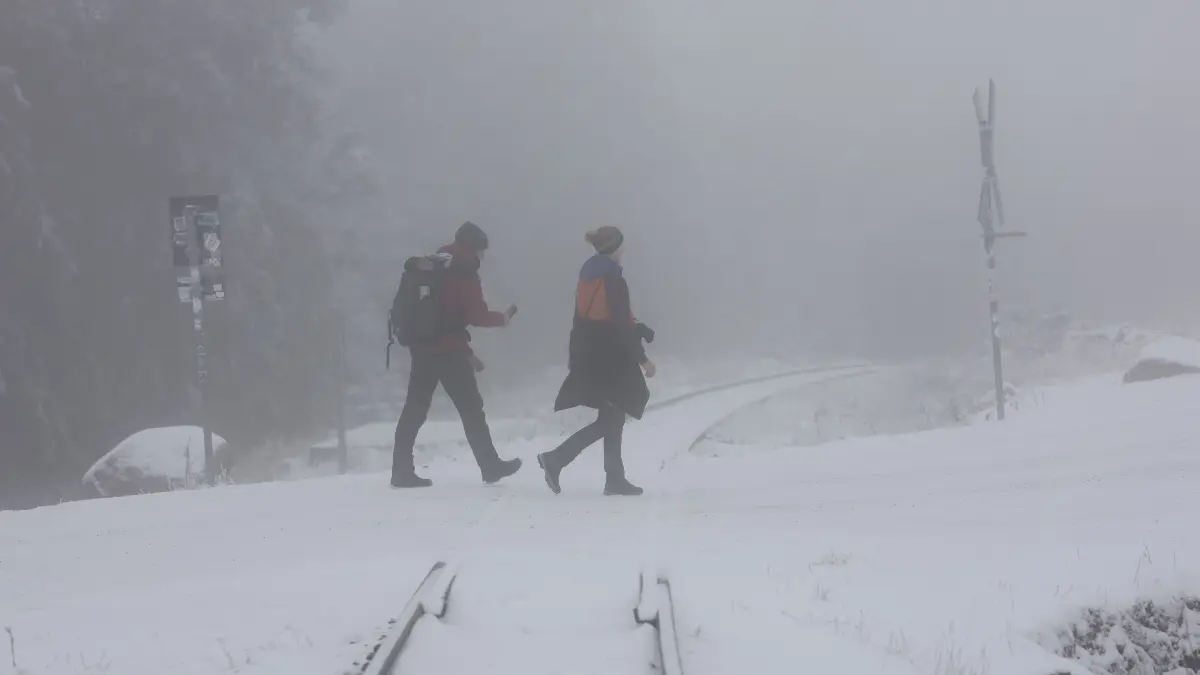 Wanderer gehen auf der Brockenstraße durch eine winterliche Landschaft. In den höheren Lagen des Harzes ist es winterlich geworden. +++ dpa-Bildfunk +++