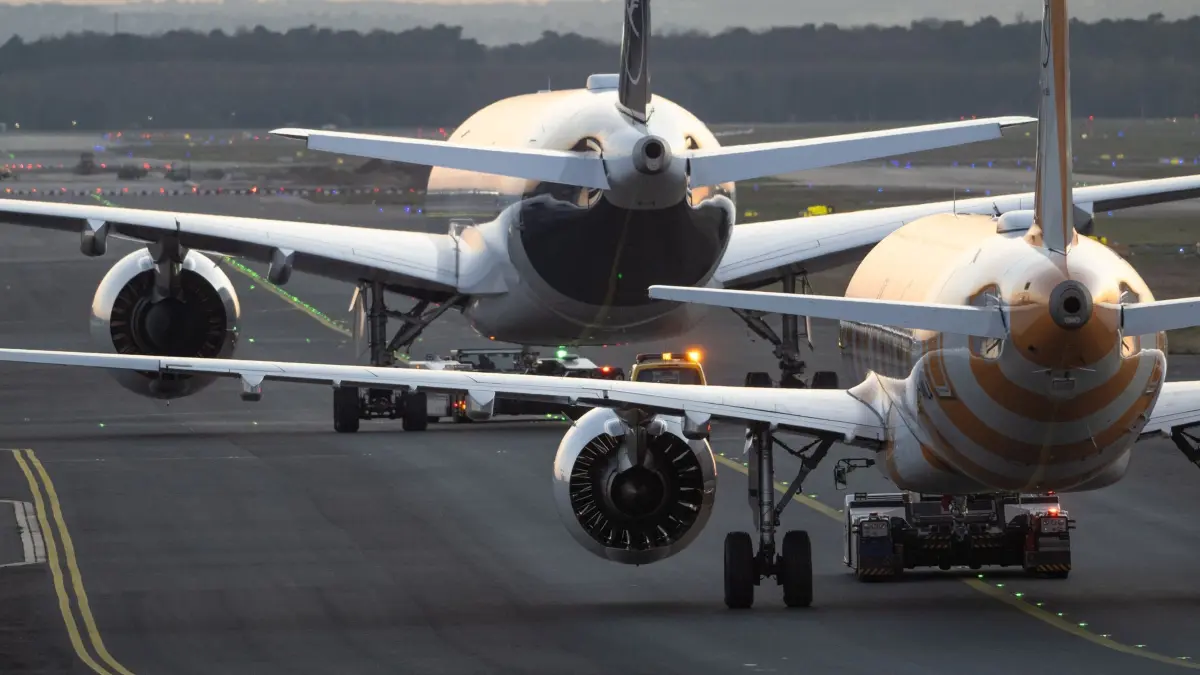 Flugzeuge im Abendlicht: ARCHIV - 04.04.2025, Hessen, Frankfurt/Main: Passagiermaschinen der Lufthansa und von Condor werden im letzten Abendlicht auf dem Flughafen Frankfurt zu ihrer Parkposition geschleppt. (zu dpa: «Bund bezahlt Asylzentren – Länder bauen Kapazitäten auf») Foto: Boris Roessler/dpa +++ dpa-Bildfunk +++