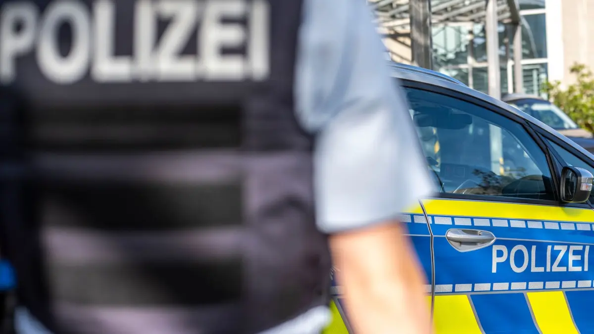 Symbolbild - Blaulicht: ILLUSTRATION - 28.09.2021, Nordrhein-Westfalen, Gütersloh: Ein Polizist steht vor einem Streifenwagen. Die Kriminalpolizei in Bielefeld hat nach einer Messerstecherei eine Mordkommission gebildet. (zu dpa: «Lebensgefahr nach Messerstecherei – Mordkommission ermittelt») Foto: David Inderlied/dpa +++ dpa-Bildfunk +++