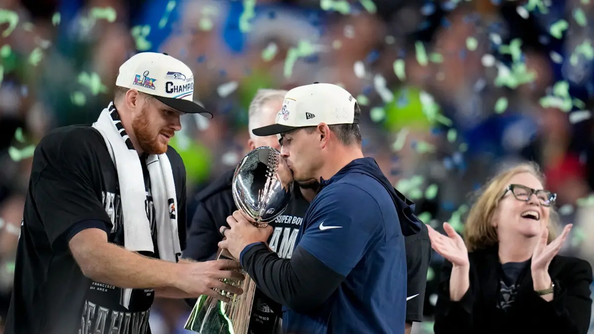 New England Patriots - Seattle Seahawks: 09.02.2026, USA, Santa Clara: American Football: Profiliga NFL, Super Bowl LX, New England Patriots - Seattle Seahawks. Der Cheftrainer der Seattle Seahawks, Mike Macdonald, küsst nach dem Sieg die Lombardi-Trophäe zwischen Quarterback Sam Darnold und dem Vorsitzenden der Seattle Seahawks, Jody Allen. Foto: Sue Ogrocki/AP/dpa +++ dpa-Bildfunk +++