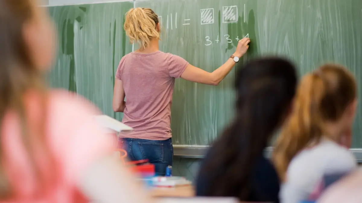 Lehrkräfte: ARCHIV - 09.06.2022, Niedersachsen, Hannover: Eine junge Lehrerin schreibt an eine Schultafel im Mathematikunterricht. (zu dpa: «Neue Studiengänge für Quereinsteiger gegen Lehrermangel») Foto: Julian Stratenschulte/dpa +++ dpa-Bildfunk +++