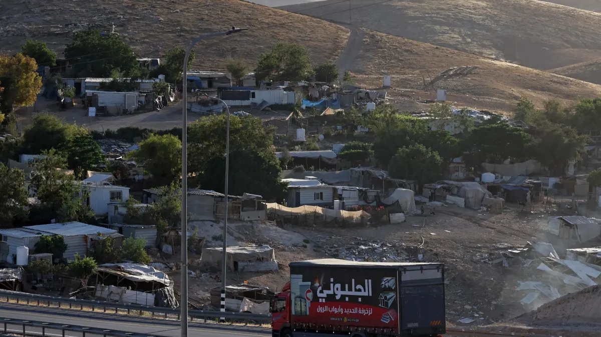 A truck drives past the Palestinian Bedouin village of Khan al-Ahmar in the Israeli-occupied West Bank on May 20, 2026. Israel's far-right finance minister Bezalel Smotrich said May 19 that the International Criminal Court prosecutor has requested an arrest warrant against him, accusing the Palestinian Authority of pushing for the move. Smotrich said he would retaliate by ordering the evacuation of the Palestinian Bedouin community of Khan al-Ahmar in the occupied West Bank. Khan al-Ahmar sits near land Israel plans to use for its controversial E1 development project that would facilitate settlement expansion in the area near Jerusalem. (Photo by AHMAD GHARABLI / AFP)
