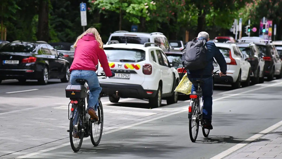 Radschnellweg,Radfahrer in Muenchen: Radfahrer fahren auf einem breiten Radweg,Radschnellweg in Muenchen im Stadtverkehr, Rad fahren ,parkende Autos,PKW,parken. *** Cyclists ride on a wide cycle path, fast cycle path in Munich in city traffic, cycling, parked cars, cars, parking