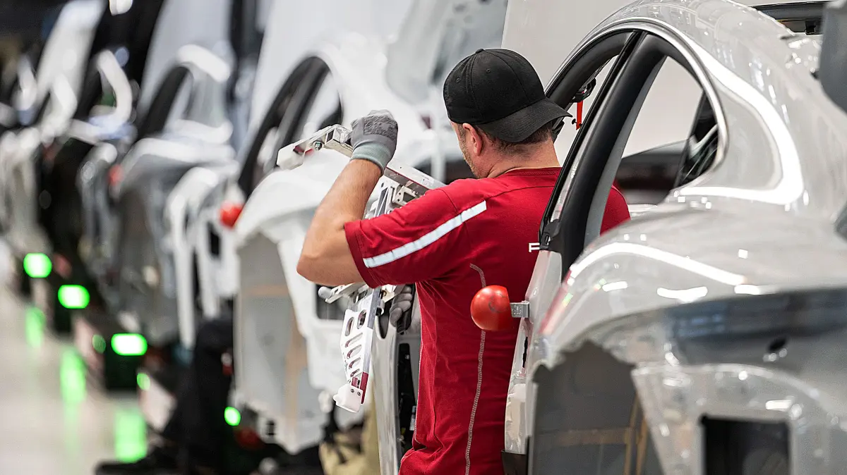 ARCHIV - 08.03.2024, Baden-Württemberg, Stuttgart: Ein Mitarbeiter der Porsche AG montiert im Stammwerk in Zuffenhausen einen vollelektrischen Porsche Taycan. (zu dpa: «Warum Porsche rund 1.900 Stellen streichen will») Foto: Marijan Murat/dpa +++ dpa-Bildfunk +++