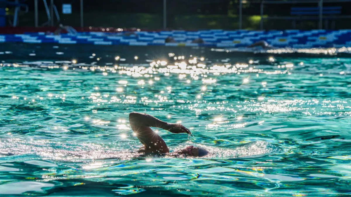 Sommerliches Wetter - Hessen: dpatopbilder - 23.05.2026, Hessen, Frankfurt/Main: Frühschwimmer ziehen im Freibad Hausen ihre Bahnen. In der Mainmetropole werden frühsommerliche Temperaturen von bis zu 30 Grad erwartet. Nach Auskunft der Mitarbeiter im Freibad Hausen wird mit einem ersten Ansturm von Badegästen gerechnet, etwas abgedämpft durch den inoffiziellen Frankfurter Nationalfeiertag, dem „Wäldchestag“ (22. bis 26. Mai). Foto: Andreas Arnold/dpa +++ dpa-Bildfunk +++