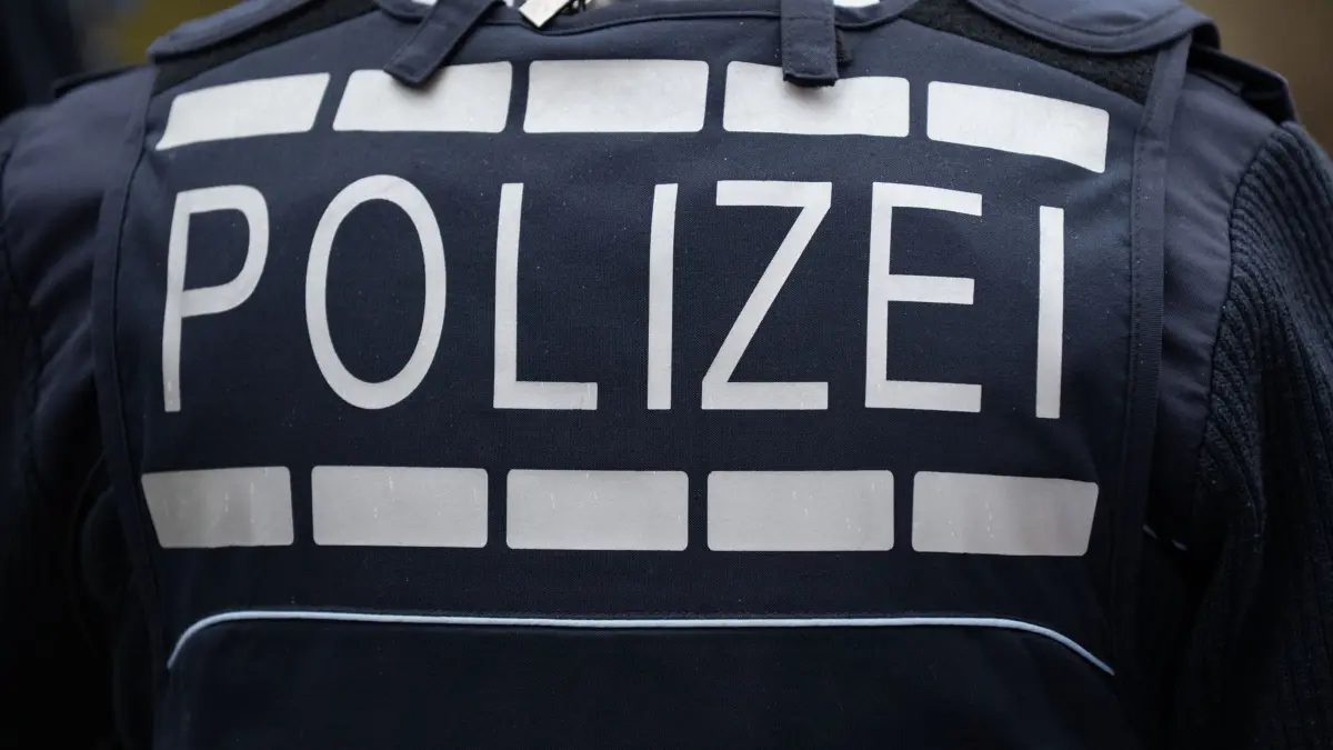 Razzia: ARCHIV - 25.02.2025, Baden-Württemberg, Dornhan: Der Schriftzug «POLIZEI» ist auf der Uniform eines Polizisten in Gundelshausen bei Dornhan (Landkreis Rottweil) zu sehen. (zu dpa: «Bei mutmaßlichem Raub mit Schreckschusswaffe geschossen») Foto: Silas Stein/dpa +++ dpa-Bildfunk +++