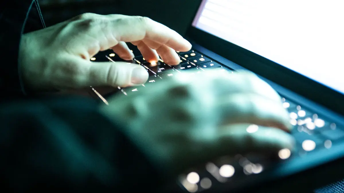 Cyberkriminalität: ILLUSTRATION - 14.12.2025, NA, Berlin: Eine Person tippt mit den Fingern auf einer beleuchteten Laptop-Tastatur.(gestellte Szene) (zu dpa: «Anlagebetrug im Internet: Mann verliert 200.000 Euro») Foto: Philip Dulian/dpa +++ dpa-Bildfunk +++